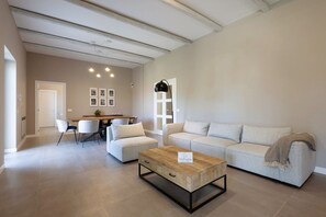 A spacious living room with a sofa, coffee table, and dining area. - WePuglia - Dimora Montaltino (Castellana Grotte)
