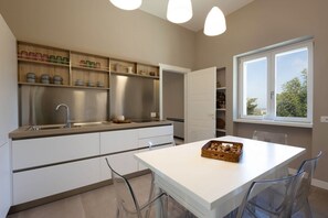 Eine moderne Küche mit weißen Schränken, einem Edelstahlkühlschrank und einem weißen Esstisch mit Stühlen.