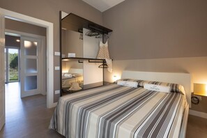 A bedroom with a large bed, a wardrobe, a mirror, and a door leading to a balcony.
