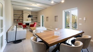 A modern living room with a wooden dining table, beige sofas, a red armchair, and a bookshelf. - WePuglia - Dimora Montaltino (Castellana Grotte)
