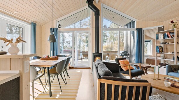 Un intérieur de chalet chaleureux comprenant un coin repas, des sièges, une cheminée et une bibliothèque.