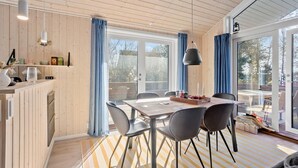 Un espace de restauration moderne avec un plafond en bois, une grande fenêtre et une table dressée pour quatre personnes.