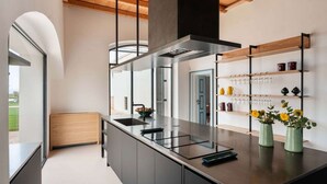 A modern kitchen with a central island, built-in appliances, and a wooden ceiling.