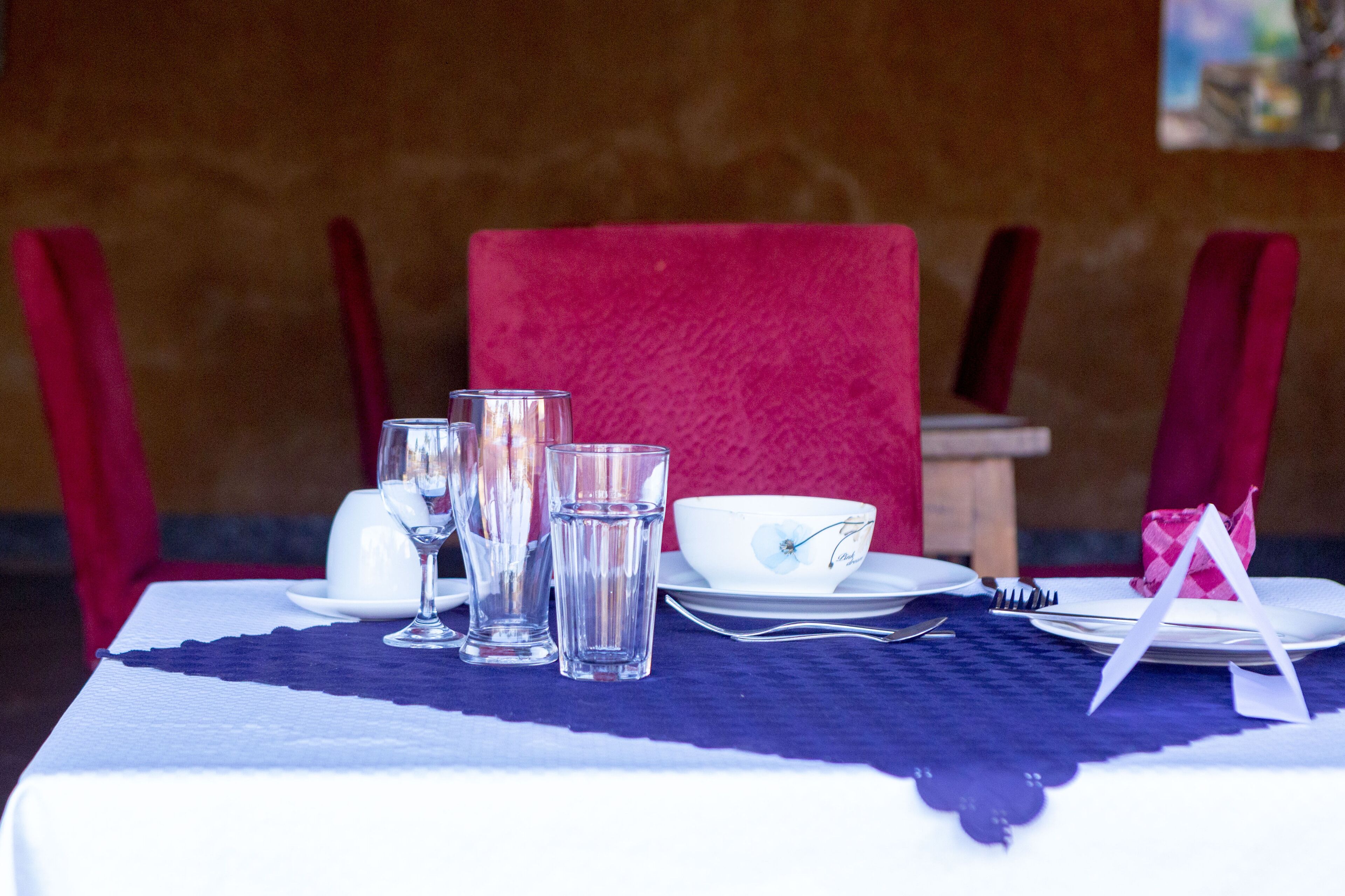 A table set with clear glasses, a white bowl, and a fork.