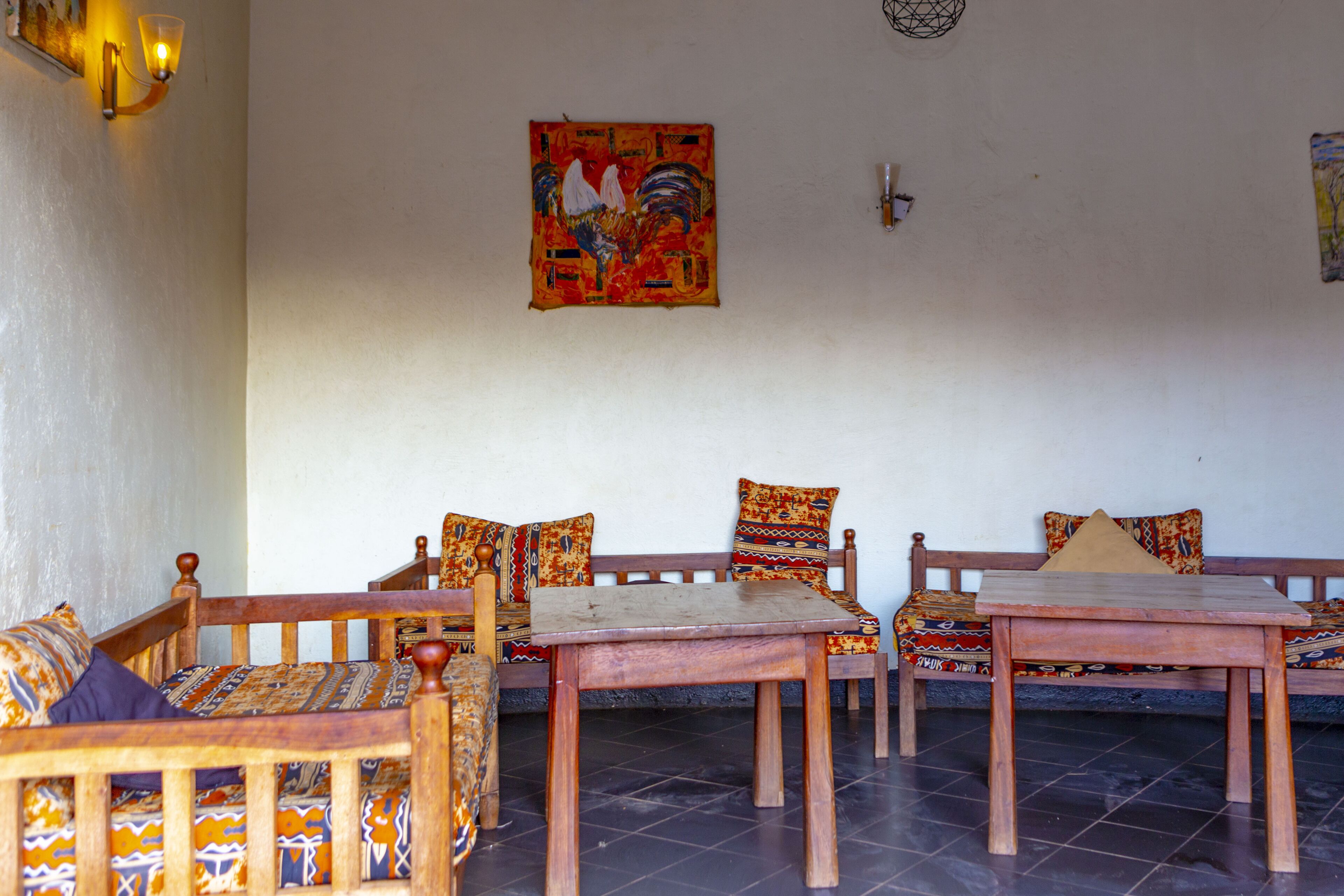 A room with a wooden sofa set, a wooden table, patterned cushions, and a wall-mounted artwork.