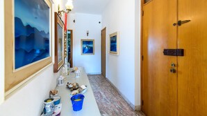 A hallway with a wooden door, framed artwork, and a table with decorative items. - Nice apartment in Porto San Giorgio (Porto San Giorgio)