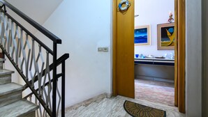 A staircase with a black metal railing leading to a room with a wooden door, a wall socket, and a framed artwork. - Nice apartment in Porto San Giorgio (Porto San Giorgio)