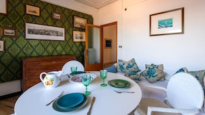 A dining area with a round table set for two, a wooden cabinet, and a green patterned wallpaper. - Nice apartment in Porto San Giorgio (Porto San Giorgio)