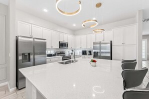 A modern kitchen with stainless steel appliances, white cabinetry, and a central island.