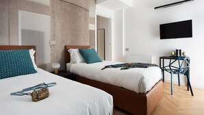 Une chambre d’hôtel avec deux lits, un téléviseur fixé au mur et une petite table avec une chaise.