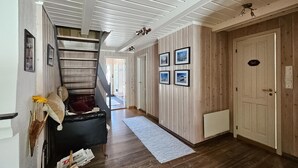Ein Flur mit Holzboden, einem schwarzen Sofa, einer Treppe und gerahmten Bildern an der Wand.