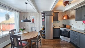 Eine moderne Küche mit einem Holzespeisetisch, Stühlen, einem Kühlschrank, einem Backofen und Pendelleuchten.