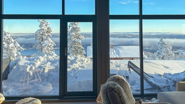 Ein Zimmer mit großen Fenstern und Blick auf einen verschneiten Berg.