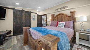 A bedroom with a wooden bed, a sliding barn door, a welcome sign, and a lamp. - Rosie's Ranch Retreat - Farm Stay (Ben Wheeler)