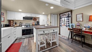 A kitchen with white cabinets, a wooden island, and a dining area with a table and chairs. - Rosie's Ranch Retreat - Farm Stay (Ben Wheeler)