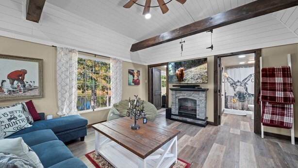 A spacious living room with a blue sofa, a wooden coffee table, and a fireplace. - Rosie's Ranch Retreat - Farm Stay (Ben Wheeler)