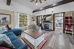 A spacious living room with a blue sofa, a wooden coffee table, and a fireplace.
