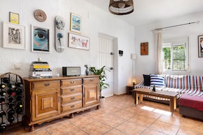 Ein Wohnzimmer mit einem Holzkabinett, einem Sofa, einem Couchtisch und einem Weineck.
