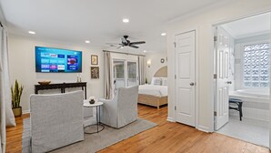 Ein modernes Schlafzimmer mit einem hölzernen Bett, einem Deckenventilator und einem Fernseher, der Nachrichtensender zeigt.