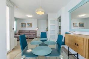 A modern dining area with a glass table, blue chairs, and a wooden cabinet.