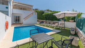 Une piscine avec des chaises longues, une table et un escalier menant à un balcon.