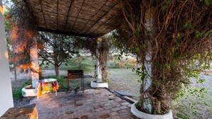 Un espacio al aire libre cubierto con piso de ladrillo, una parrilla y plantas en macetas.