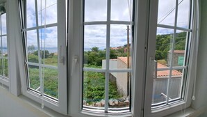 Een kamer met grote ramen, met uitzicht op een groen landschap en gebouwen.