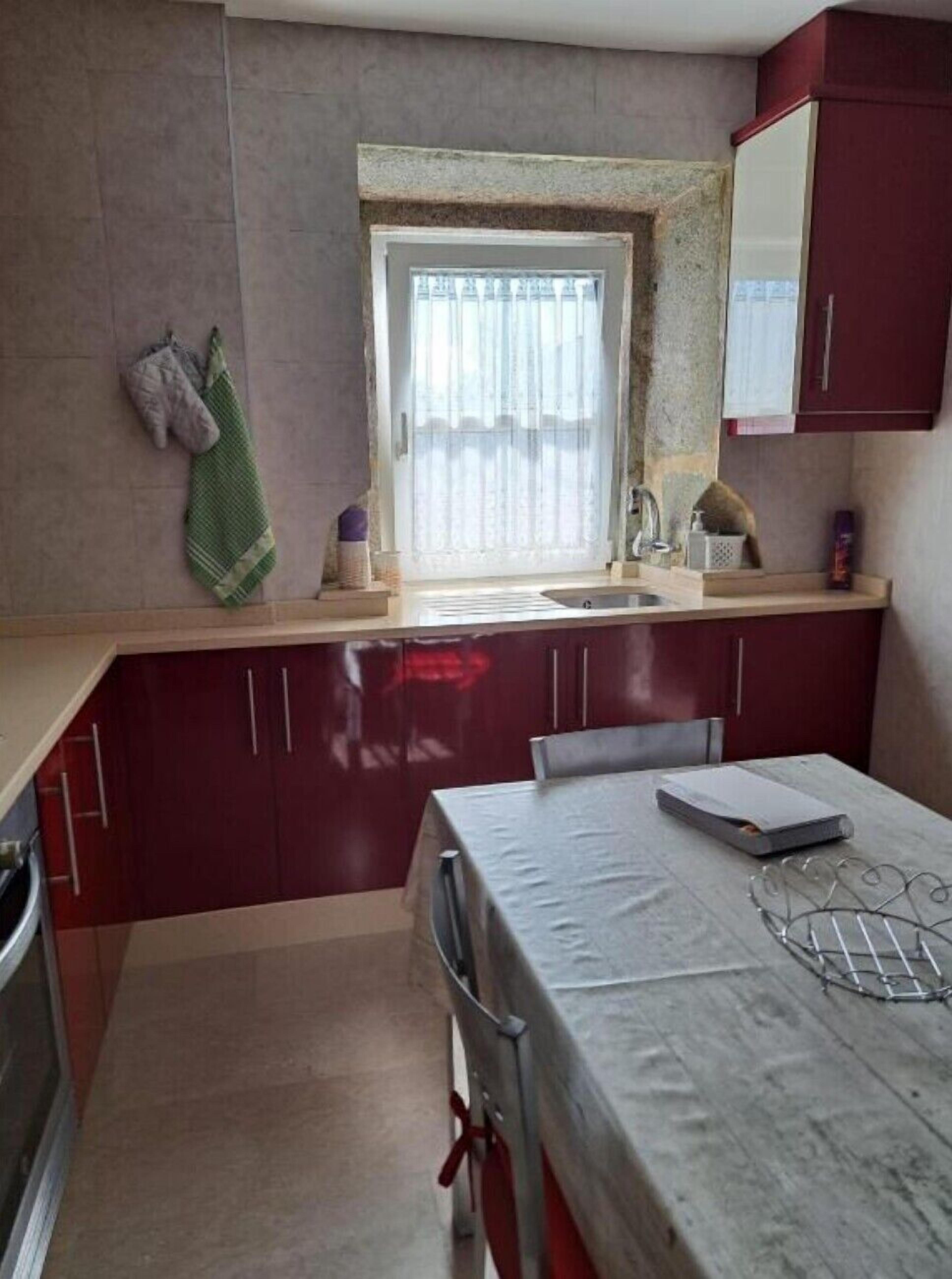 Una cocina compacta con ventana, un fregadero y una zona de comedor con mesa.