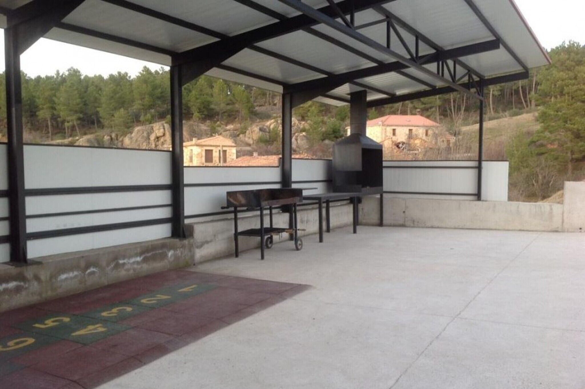 Un patio exterior con una parrilla, una mesa y un banco.