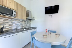 Een moderne keuken met een magnetron, fornuis, spoelbak en een eethoek met een tafel en stoelen.