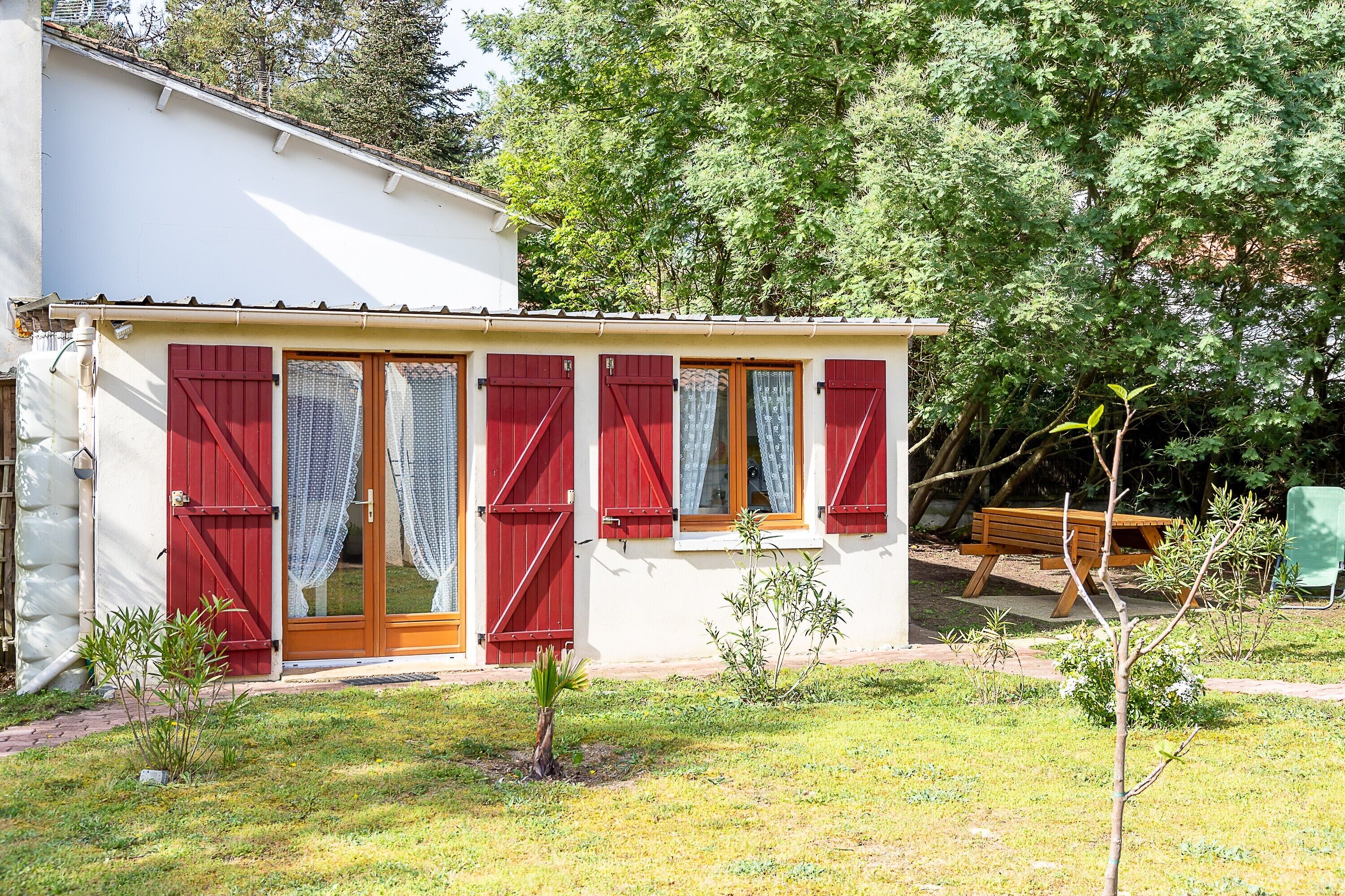 A small house with red shutters, a wooden door, and a small garden.
