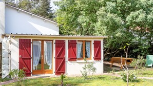 Een klein huis met rode luiken, een houten deur en een kleine tuin.