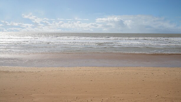 Een strand met een zandstrand en golven.