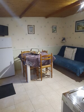 Un coin repas comprenant une table et des chaises, un canapé, un réfrigérateur et des tableaux accrochés au mur.