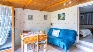 Een kamer met een eettafel, stoelen, een blauwe bank en een trap naar een andere kamer.