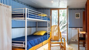Een kamer met stapelbedden, een rieten stoel en een houten bureau.