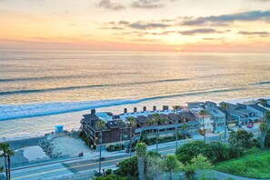 A coastal hotel with a beachfront view, multiple stories, and a parking area.