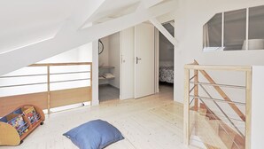 Camera in stile loft con soffitto spiovente, un letto a castello in legno, una piccola scrivania e una finestra.