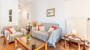 Un salon avec deux canapés gris, une table basse en bois, une lampe et des tableaux encadrés accrochés au mur.