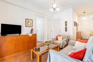 Uma sala de estar com televisão, sofá, mesa de centro e armário.