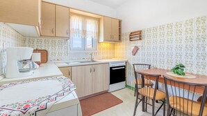 Une cuisine compacte avec des meubles en bois, un four encastré, un évier et un coin repas comprenant une table et des chaises.