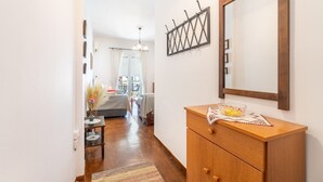 Un couloir menant à une chambre à coucher, où se trouvent une commode en bois, un miroir et un élément décoratif mural.