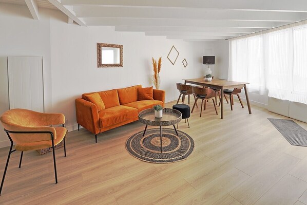 Un salon comprenant un canapé, des fauteuils, une table basse, une table à manger et une lampe.