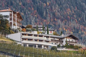 Un hôtel à plusieurs étages, doté de balcons, situé dans une région montagneuse aux couleurs automnales.