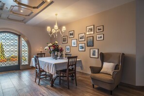 Un espace repas comprenant une table, des chaises, un lustre et des tableaux encadrés accrochés au mur.