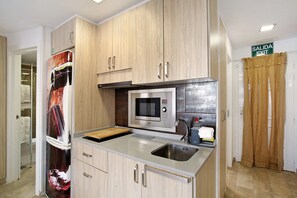 Une cuisine compacte équipée d’un four à micro-ondes, d’un évier et de meubles de rangement en bois.