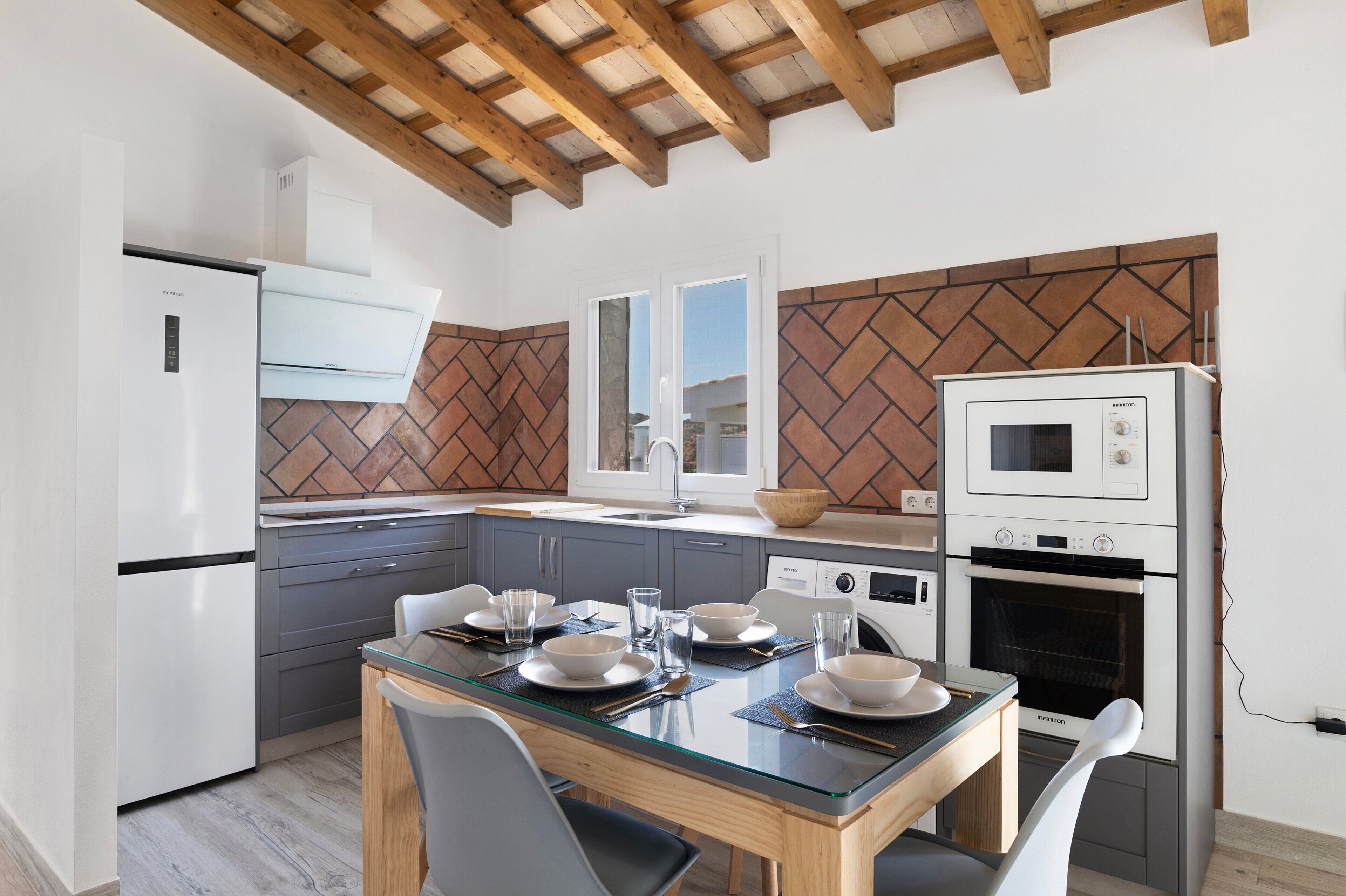 A modern kitchen with a dining table set for four, a built-in oven, and a microwave.