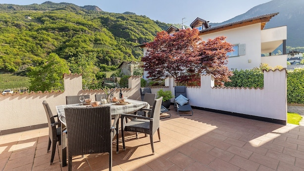 A patio with a table and chairs, a potted plant, and a view of a mountain. - Apartment 'Kreutnerbinderhof' with Mountain View, Private Terrace and Wi-Fi (Terlano)