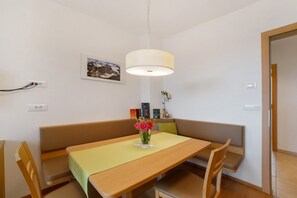 A dining area with a table, chairs, a bench, a hanging light fixture, and a wall-mounted picture.