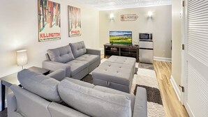 Ett modernt vardagsrum med grå soffor, ett soffbord, en tv och en öppen spis.